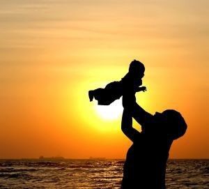 Fotografi: Barn holdes opp i været av foreldre, solnedgang i bakgrunnen. 